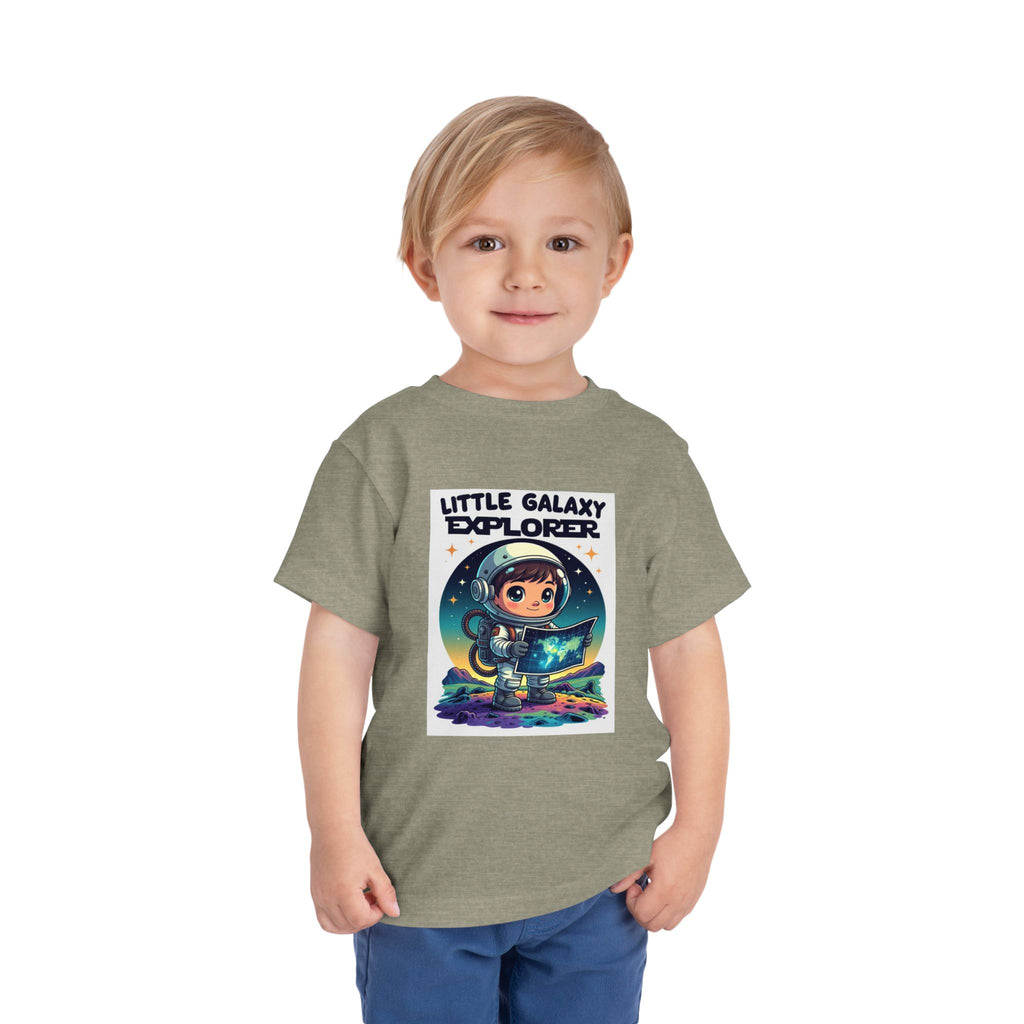 Little Galaxy Explorer kids t-shirt in light green with a cartoon astronaut holding a map and colorful space elements.